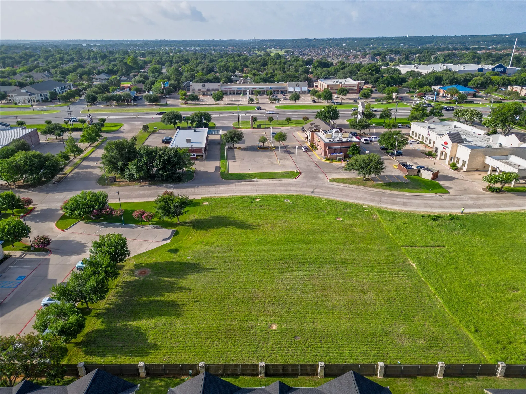 Expansive green space bordered by paved roads and mature trees
