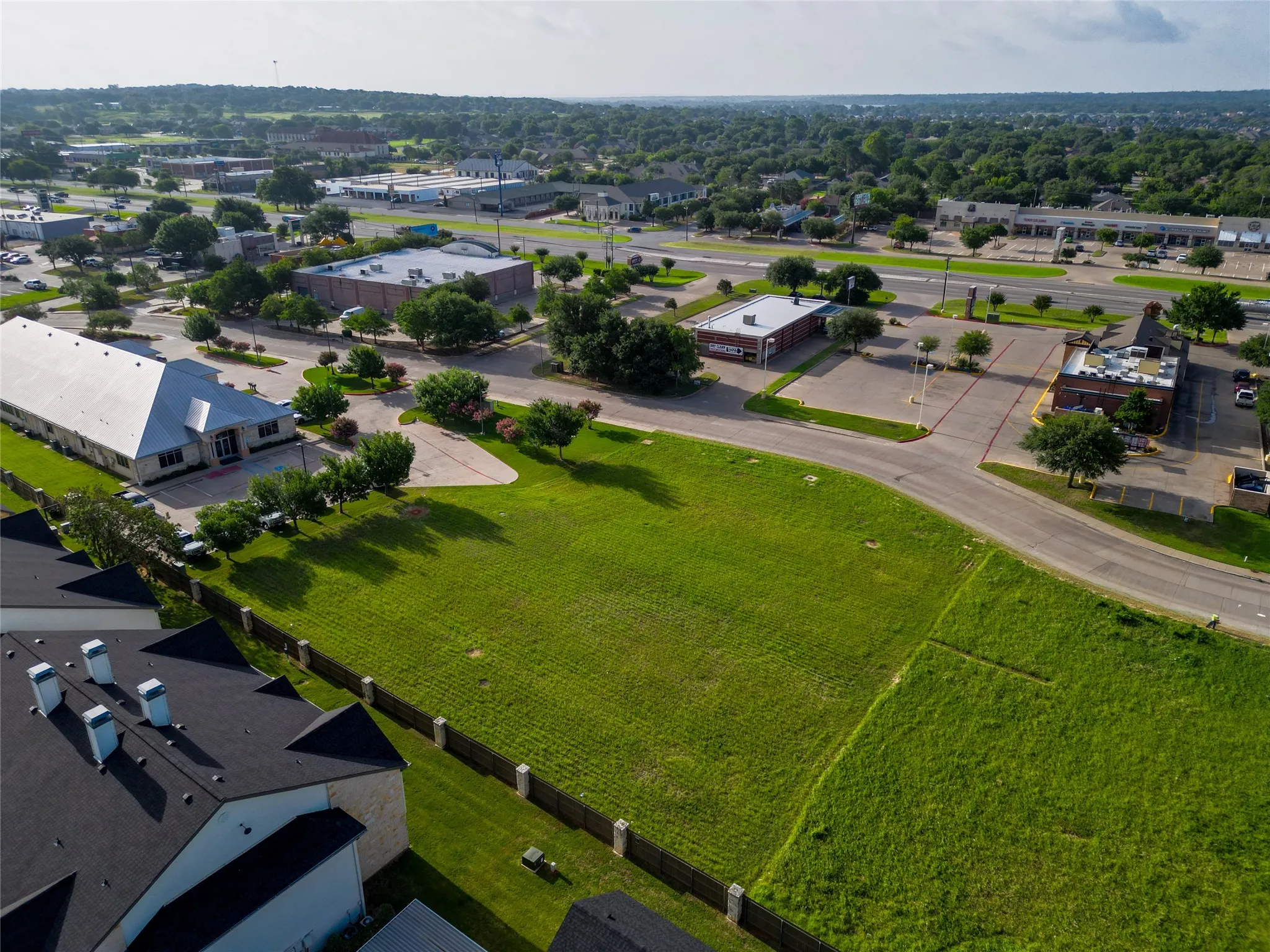 Expansive green space with clear lot boundaries, bordered by a wooden fence, and featuring direct road access