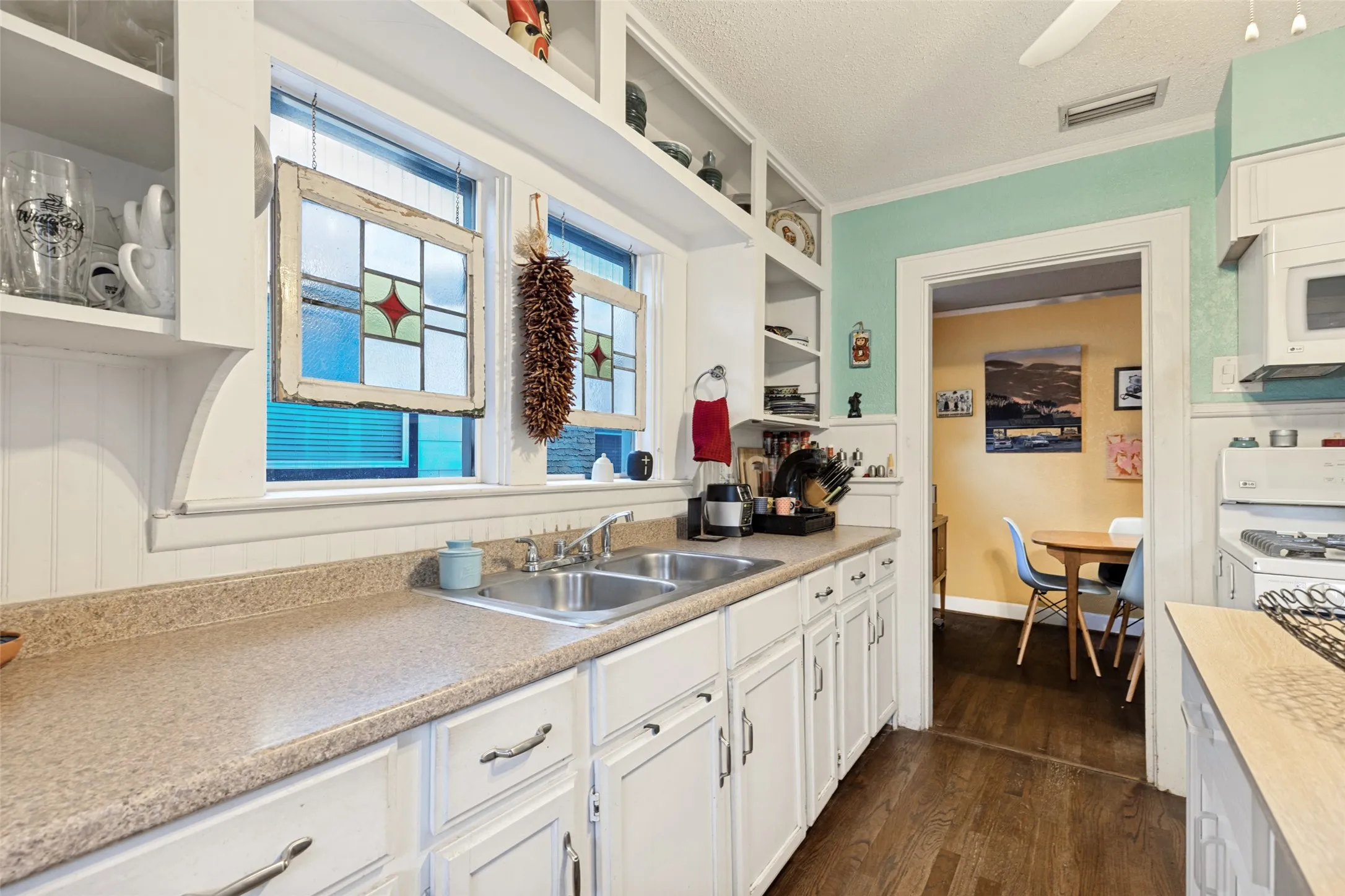Bright and full of character, the Kitchen features abundant cabinetry, open shelving, a gas range, and built-in microwave.
