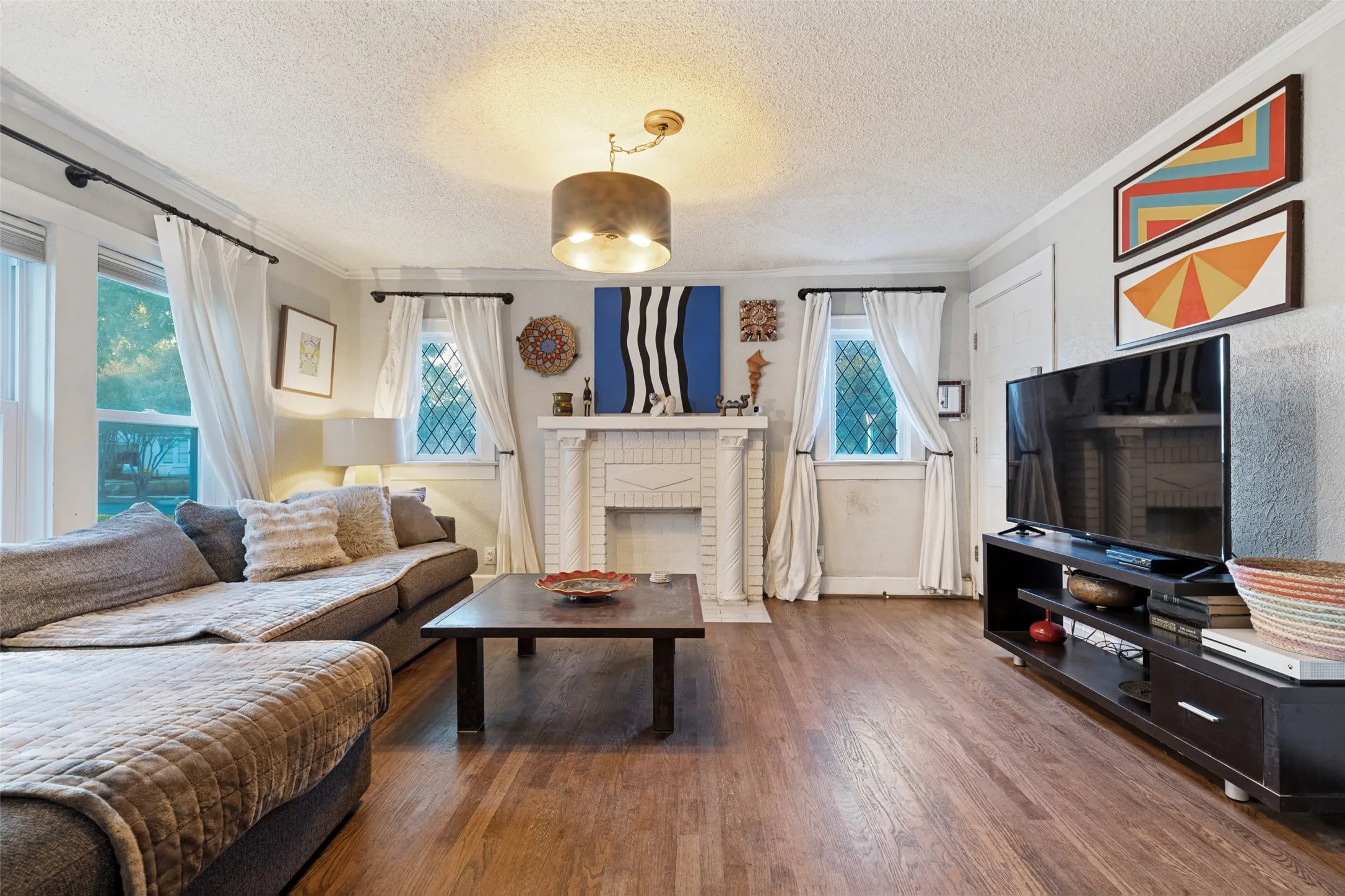 Warm and collected, the Living Room pairs hardwood floors and original leaded-glass windows with an ornate decorative fireplace and sculptural mantel.
