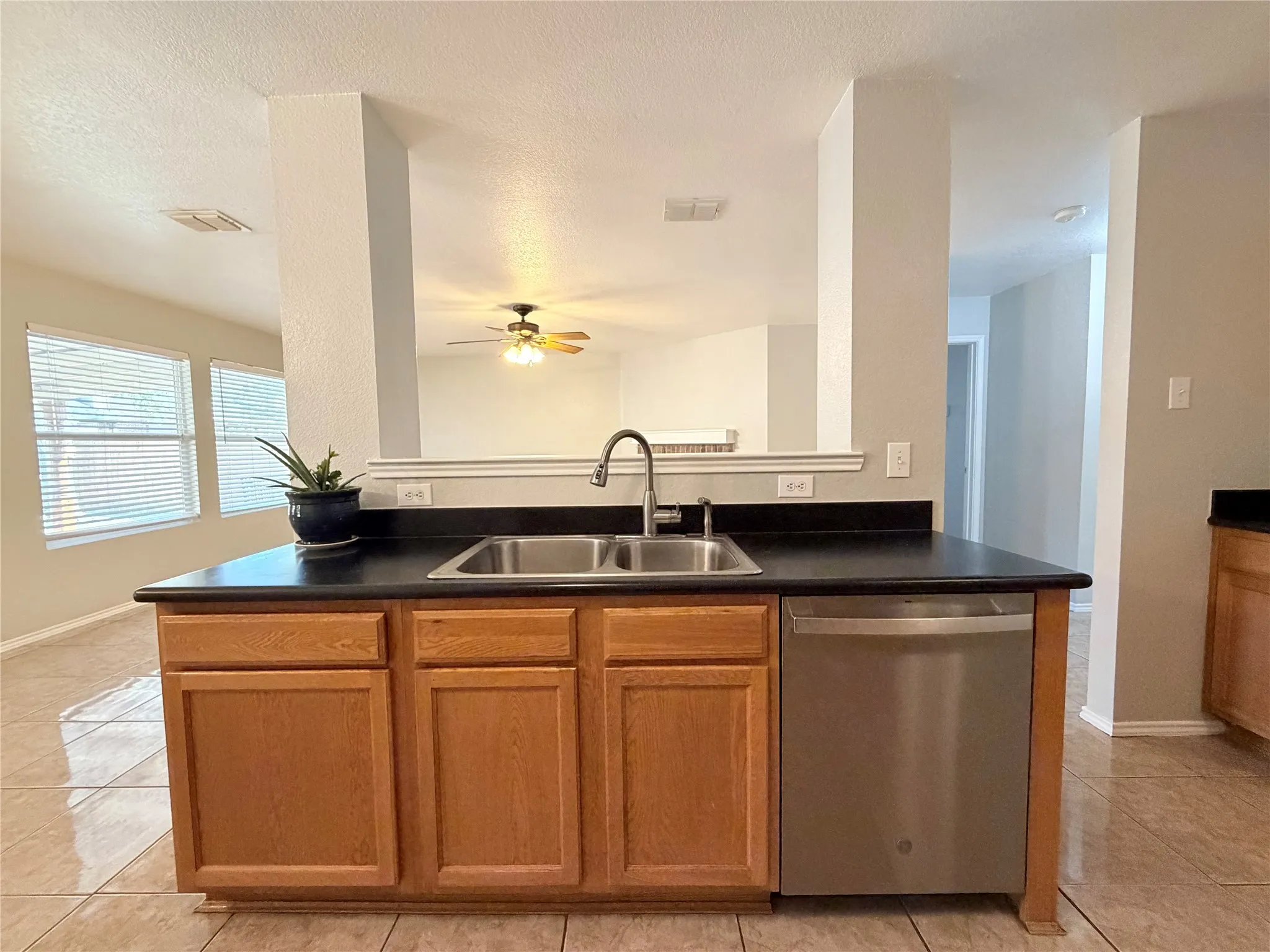 Kitchen island with double basin stainless steel sink, stainless steel dishwasher, and wood cabinetry