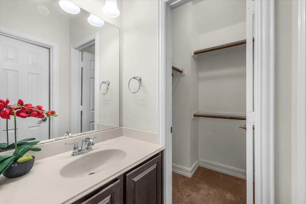 Vanity with integrated sink, chrome faucet, full-width mirror, and overhead vanity lighting