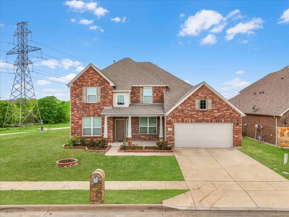 Two-story brick exterior with a pitched roof, front-facing garage, covered entry porch, and a concrete driveway