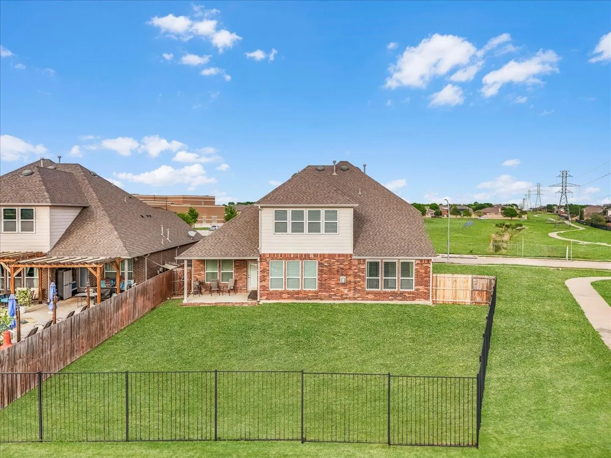 Brick and siding exterior, fenced backyard, concrete patio, multiple windows, and a paved walkway