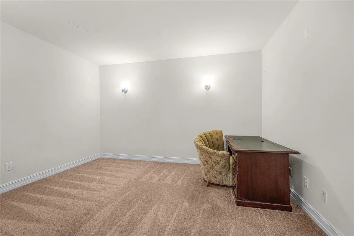 Neutral carpeted flooring, white wall paint, and wall-mounted sconce lighting