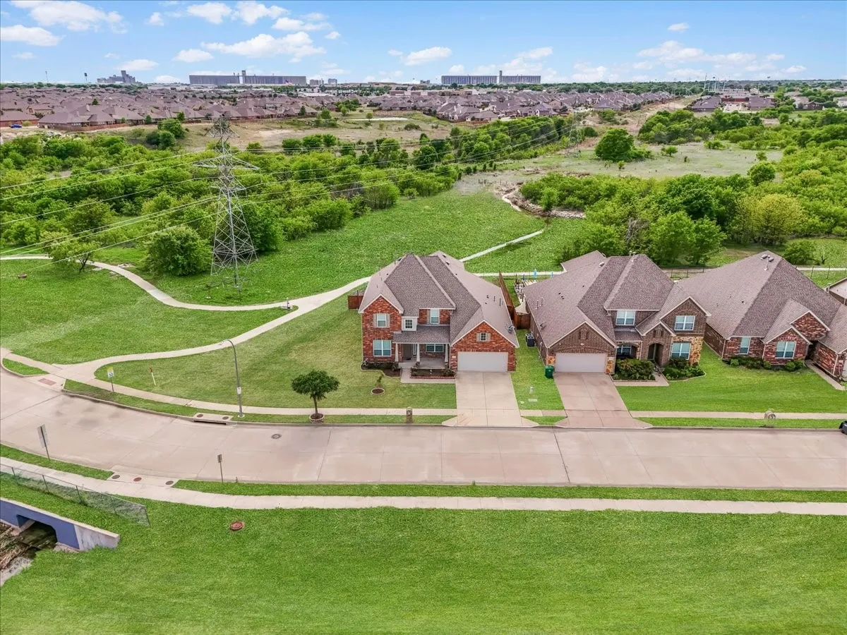 Suburban residential setting with multiple single-family homes featuring brick and stone exteriors, asphalt shingle roofs, and attached garages