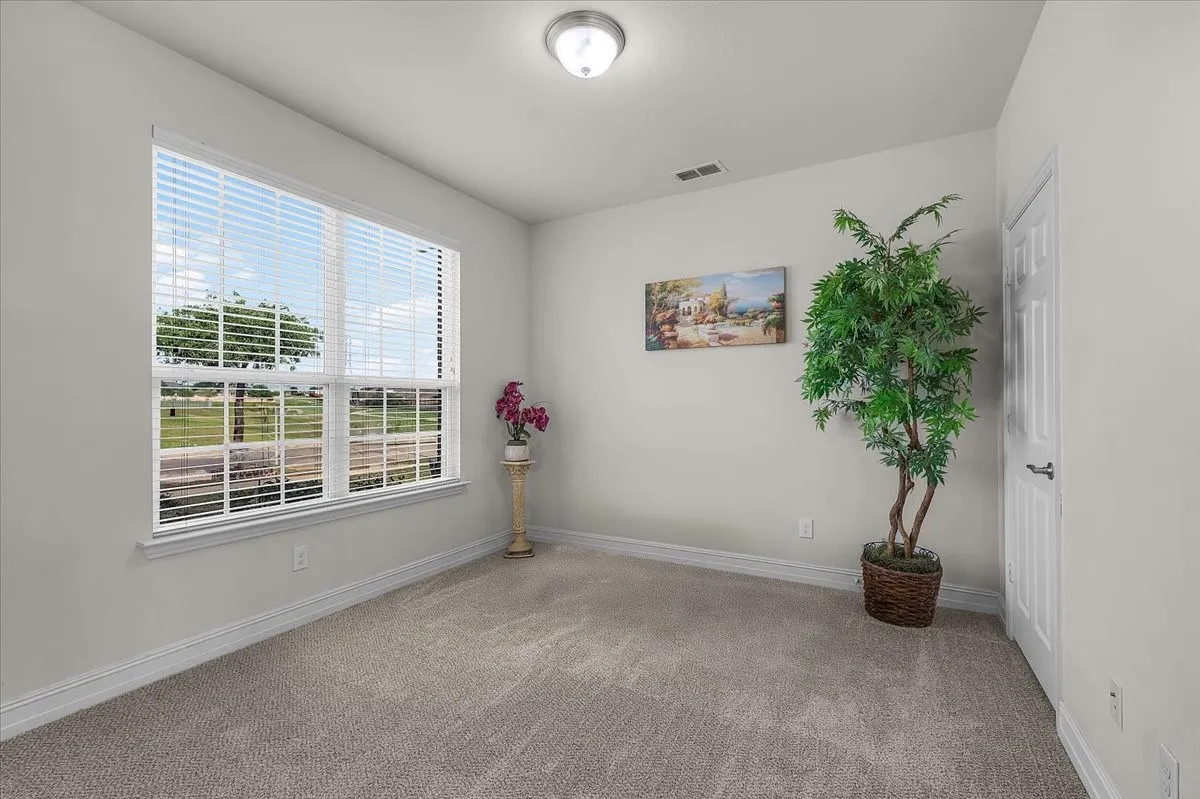 Recessed ceiling light, carpeted flooring, large window with horizontal blinds, white interior door, and neutral wall color