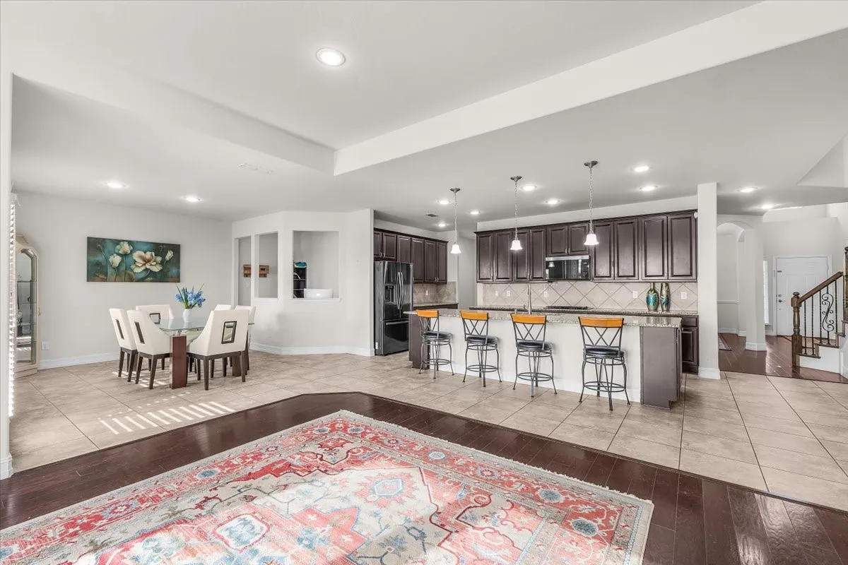 Spacious open-concept layout featuring recessed lighting, a dining area, and a kitchen with dark cabinetry, stainless steel appliances, and a tiled backsplash