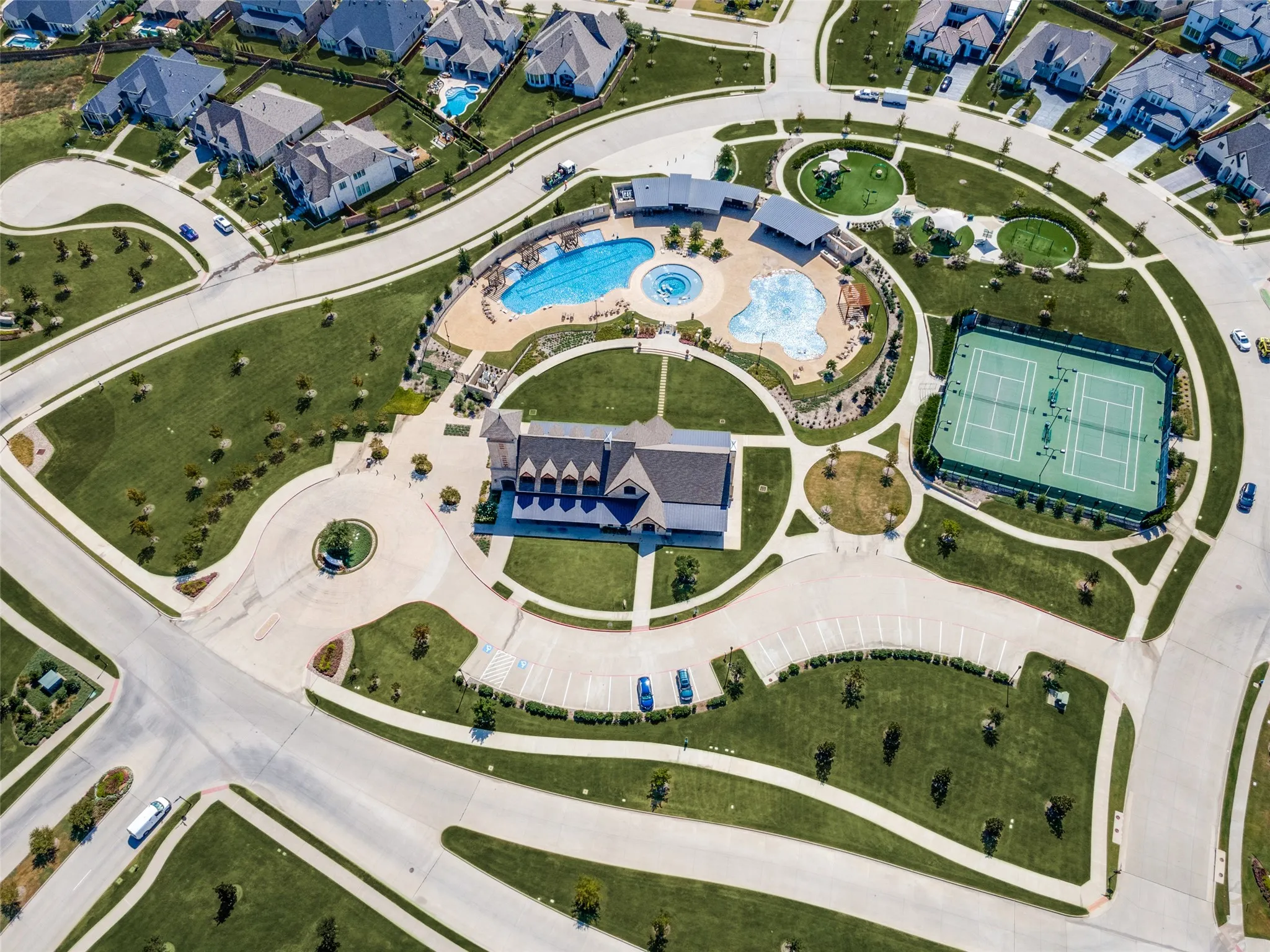 Community with extensive green spaces, a central clubhouse, multiple swimming pools, a tennis court, and walking paths