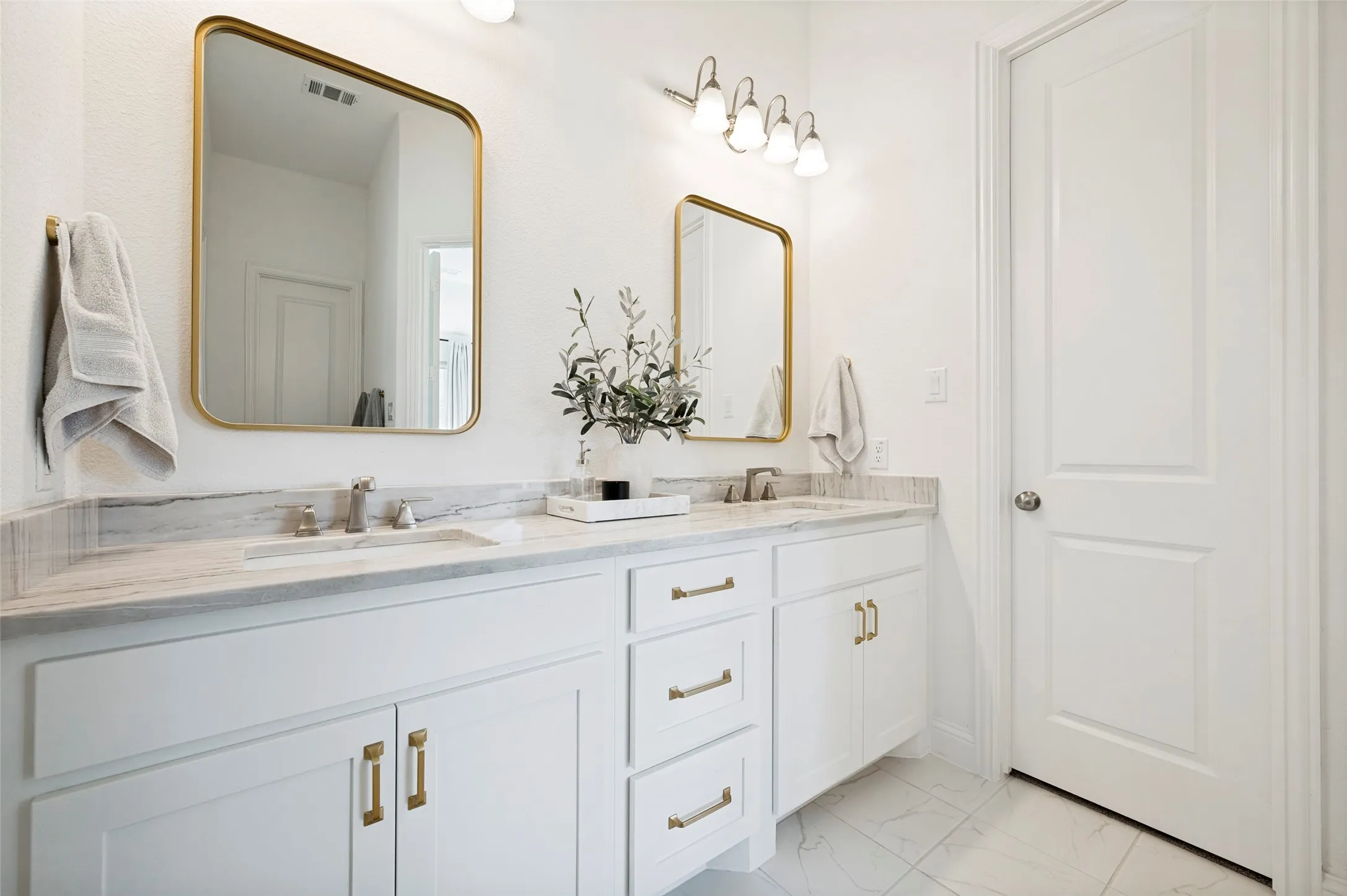 Dual vanity with white cabinetry and gold-tone hardware