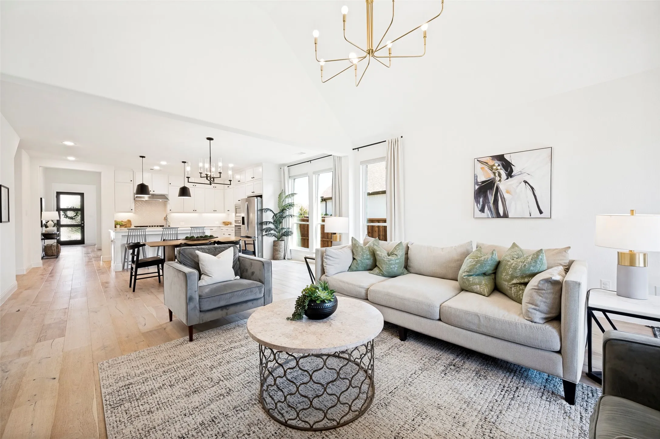Vaulted ceiling with an angular chandelier, light wood-finish flooring, and white walls
