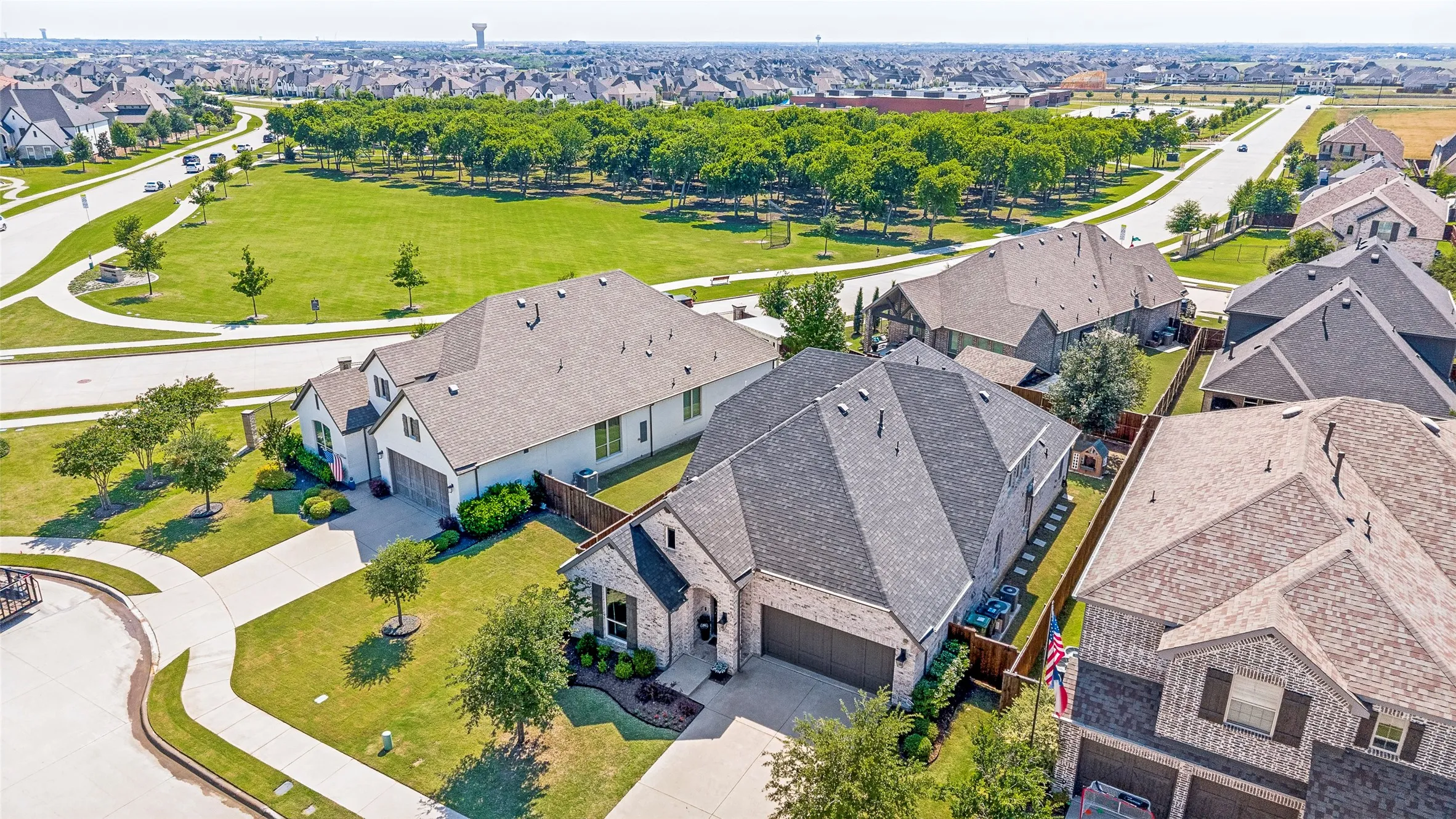Stone and brick-finish exterior with an attached garage, landscaped front yard, and a fenced backyard