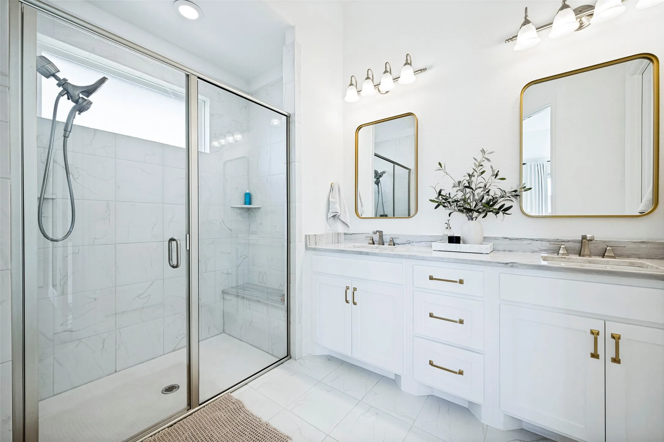 Dual vanity with white cabinetry, gold-toned hardware, and rectangular mirrors