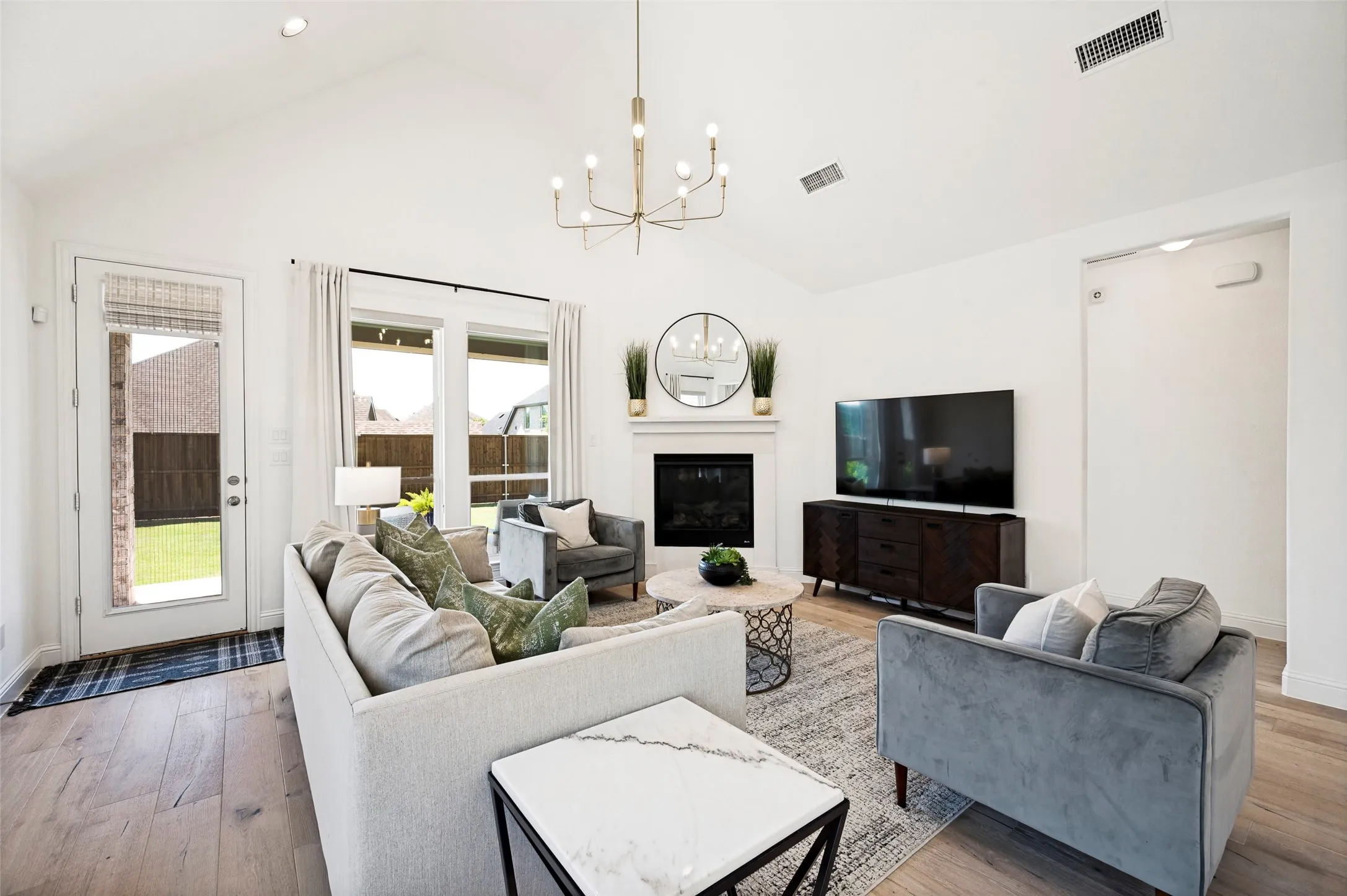 Vaulted ceiling with recessed lighting, wood-finish flooring, white fireplace with mantle, and glass-paneled exterior door
