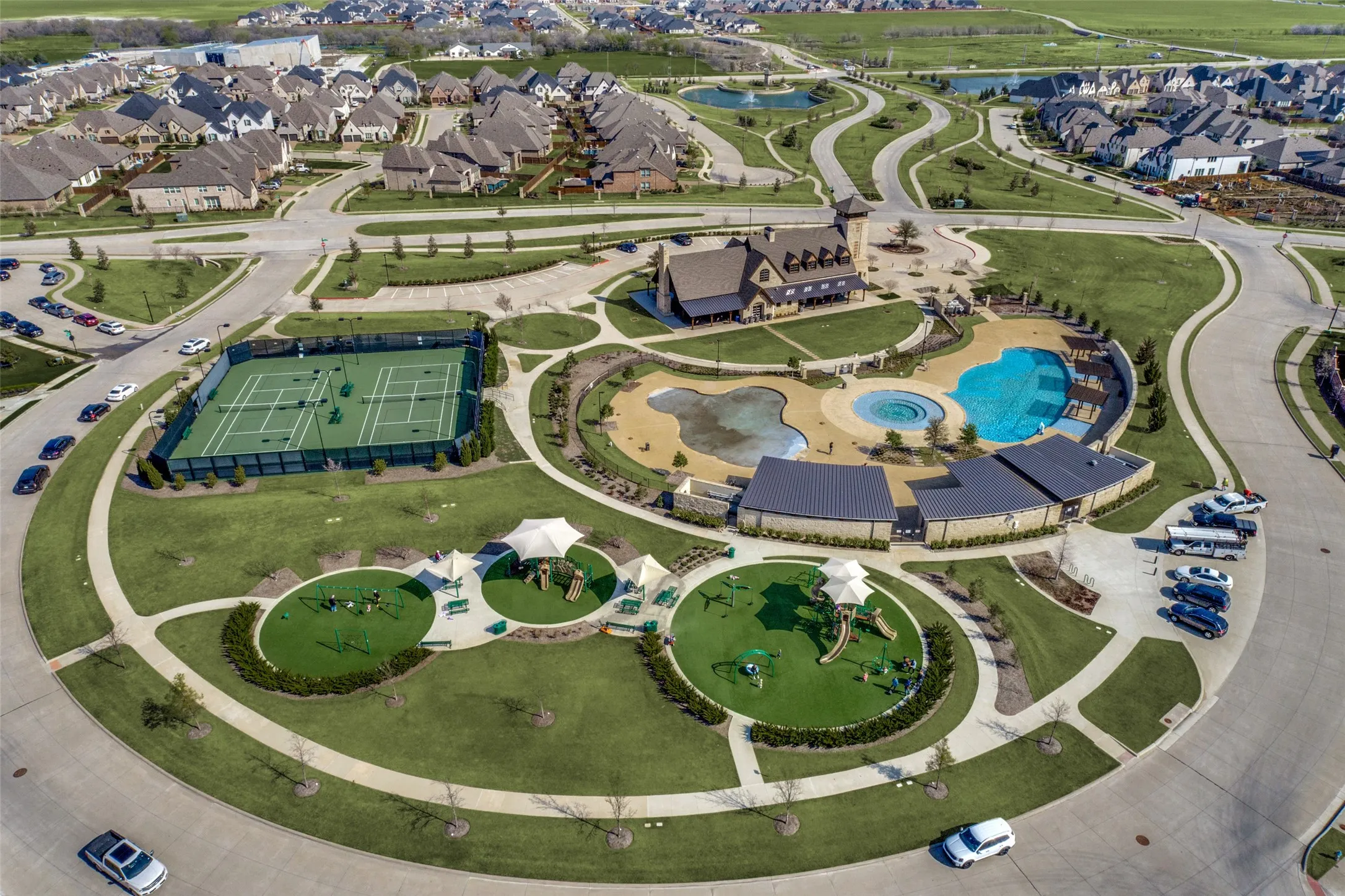 Community features include multiple tennis courts, a large swimming pool with a splash pad, a dedicated clubhouse building, and two separate playground areas