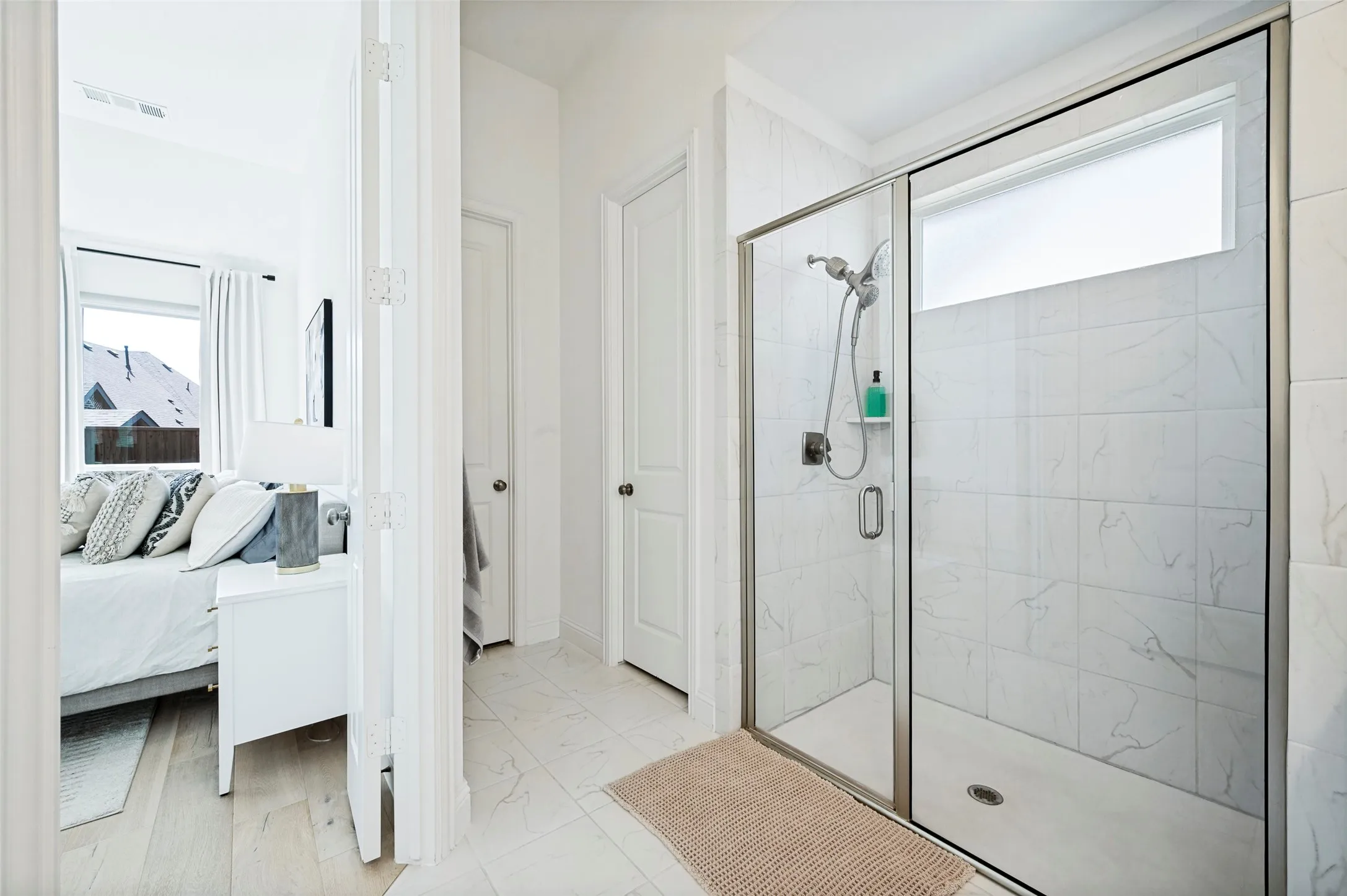 Walk-in shower with clear glass enclosure and tile surround