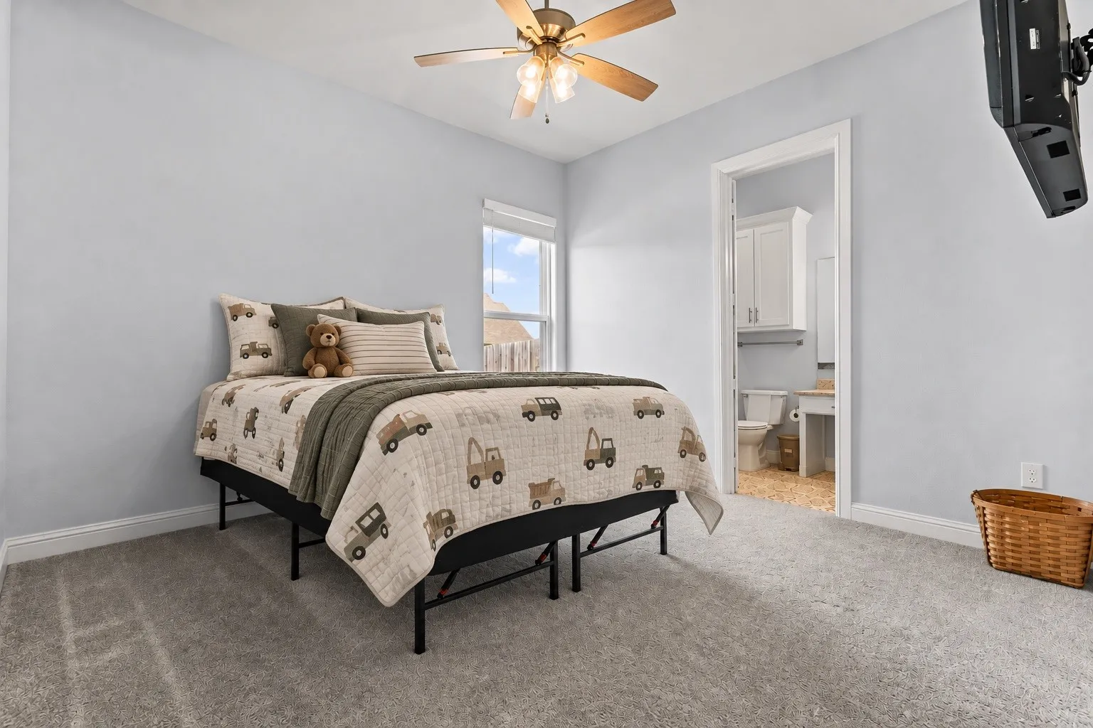 Carpeted flooring, ceiling fan with integrated lighting, window with a blind, and an open doorway to a bathroom