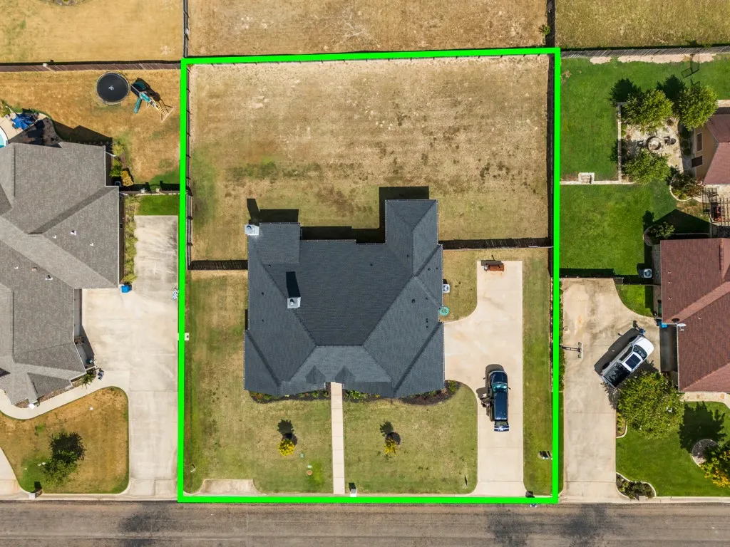 Expansive lot with a pitched roof residence, a front yard with mature landscaping, and a paved driveway
