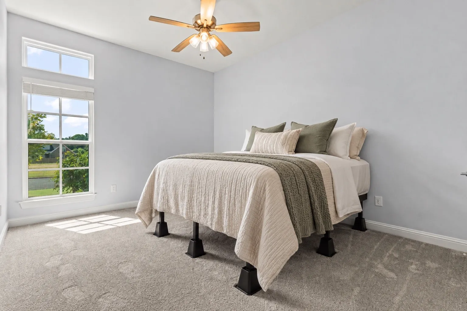 Neutral-toned carpeting, ample natural light, and a ceiling fan with integrated lighting