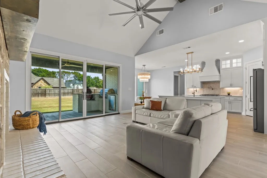 Vaulted ceiling, ceiling fan, wood-finish flooring, sliding glass doors, and recessed lighting