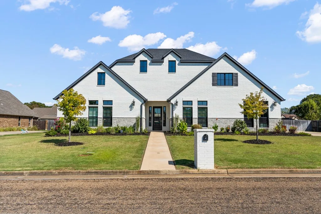 White brick exterior with a dark shingle roof and black-framed windows