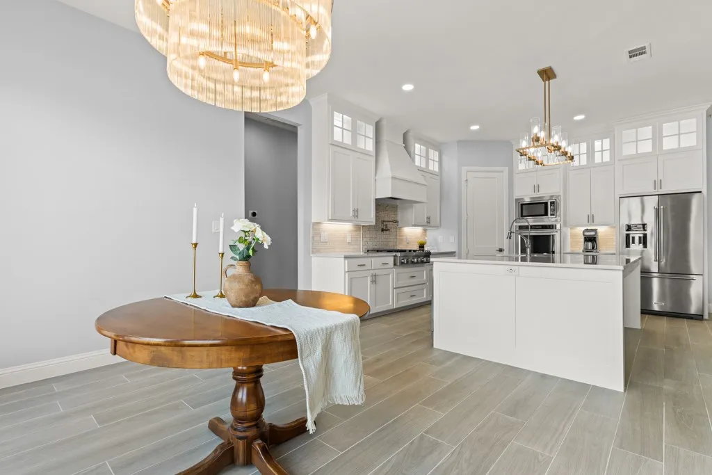 Spacious kitchen with a central island, white cabinetry, stainless steel appliances, and wood-finish flooring