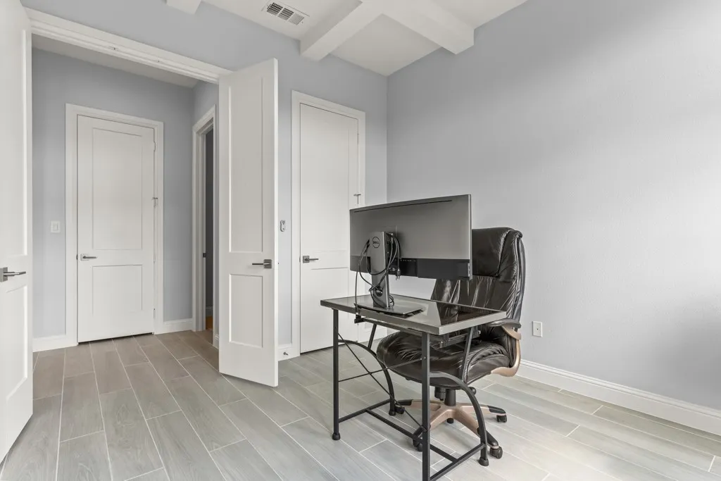 Light wood-finish flooring, white paneled interior doors, and a beamed ceiling