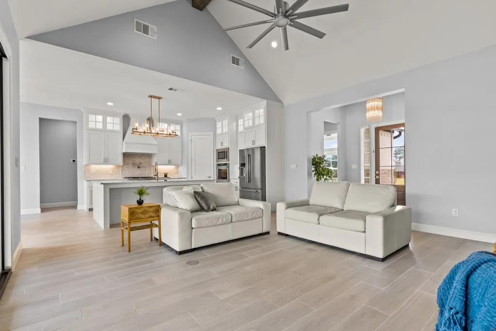 Vaulted ceiling with exposed wood beam, wood-finish flooring, recessed lighting, and a contemporary ceiling fan