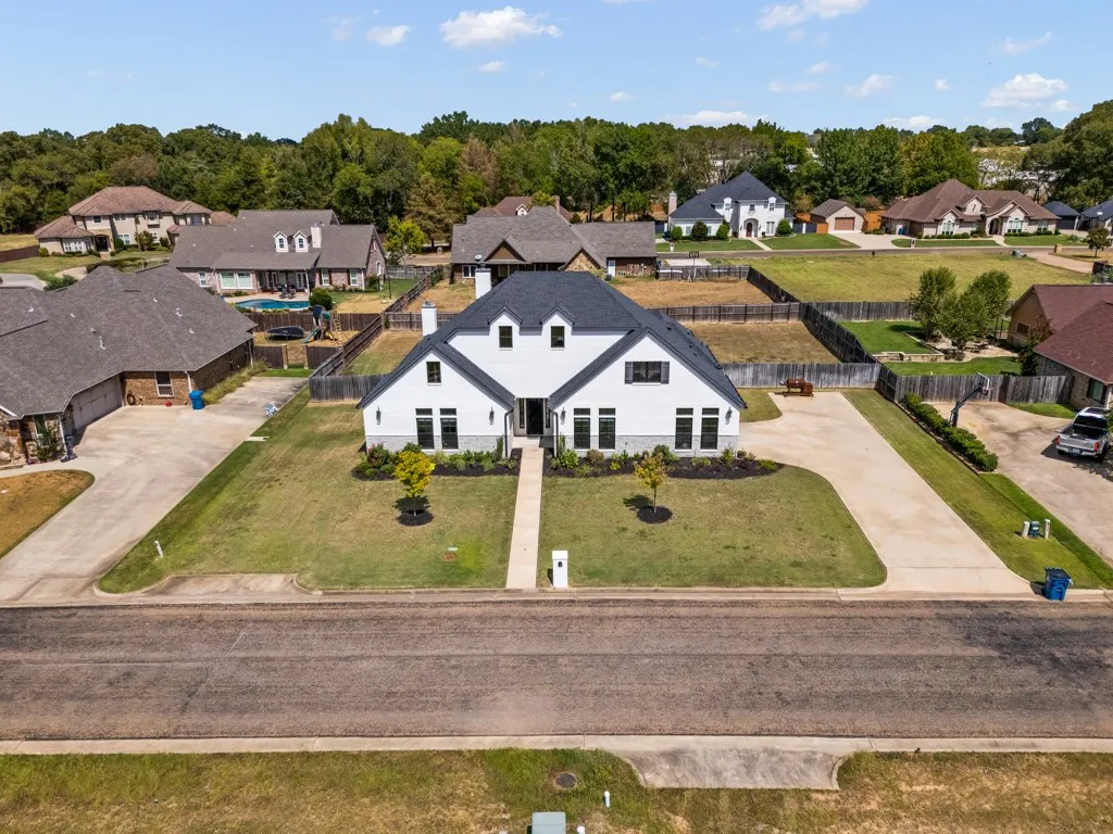White two-story exterior with a dark roof, dark window trim, a prominent front walkway, and an attached driveway