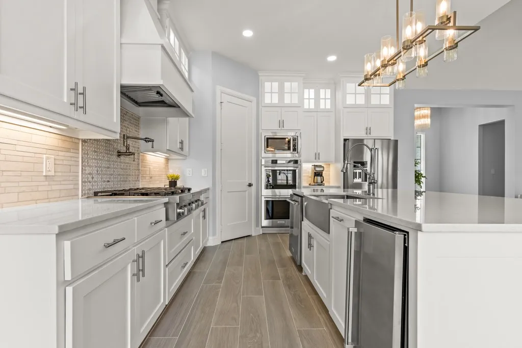 Gourmet kitchen with white cabinetry, stainless steel appliances, a large island, tile backsplash, and wood-finish flooring