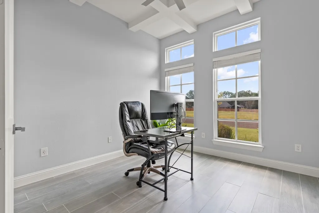 Wood-finish flooring with high ceilings, large windows, and coffered ceiling details