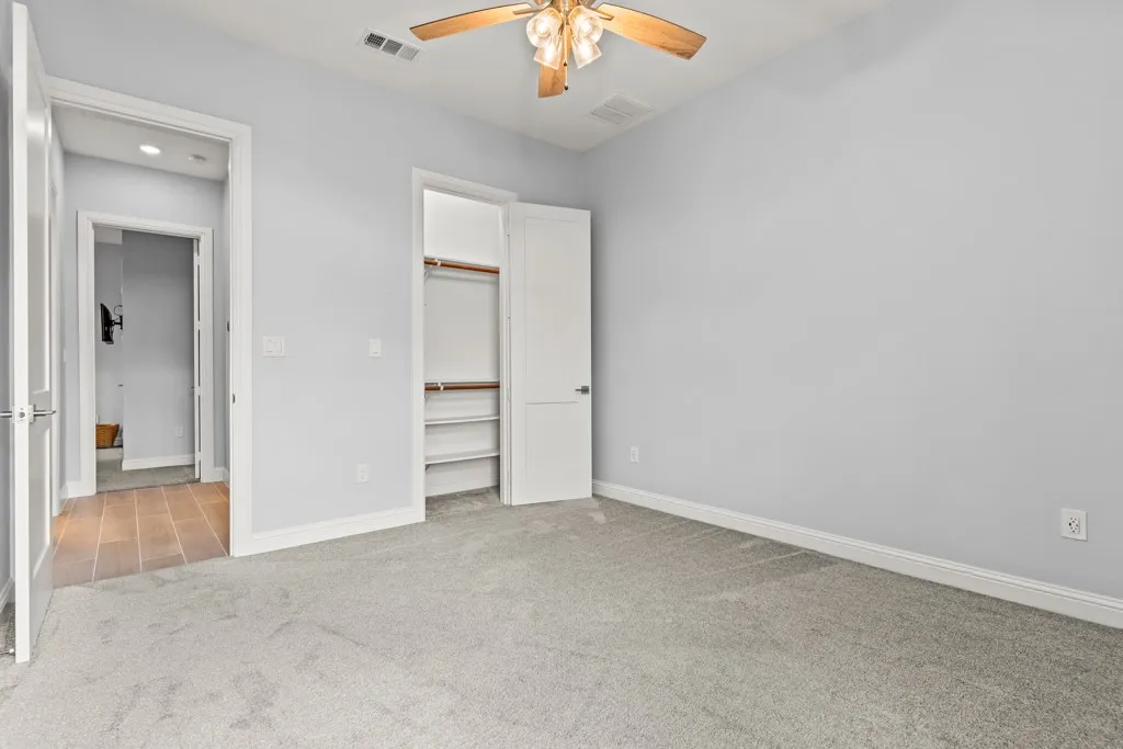 Neutral wall palette, ceiling fan with integrated lighting, built-in closet shelving, and wood-finish flooring
