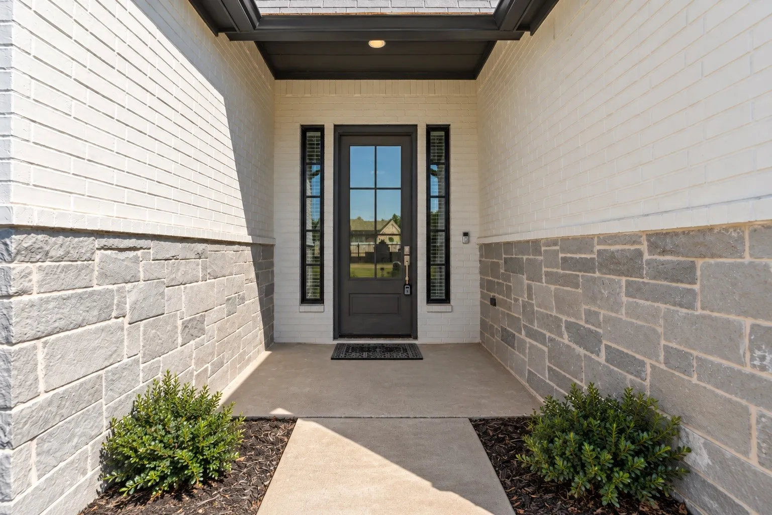 Entryway featuring white brick siding and a stone-clad lower facade