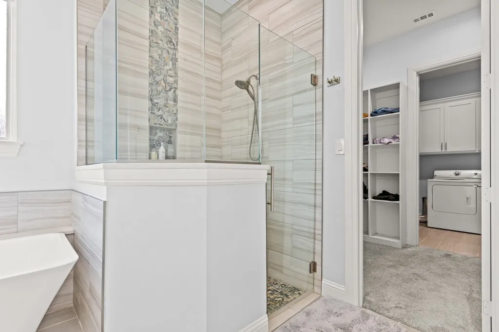 Glass-enclosed shower with stone tile surround and built-in niche