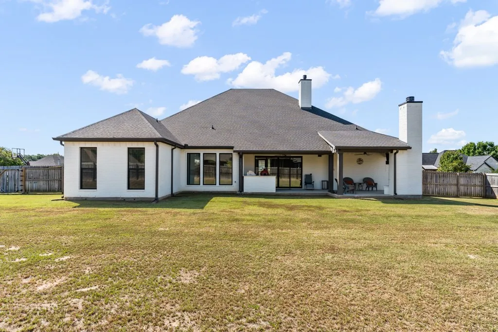 White brick exterior with a dark shingle roof, featuring multiple large windows with dark frames