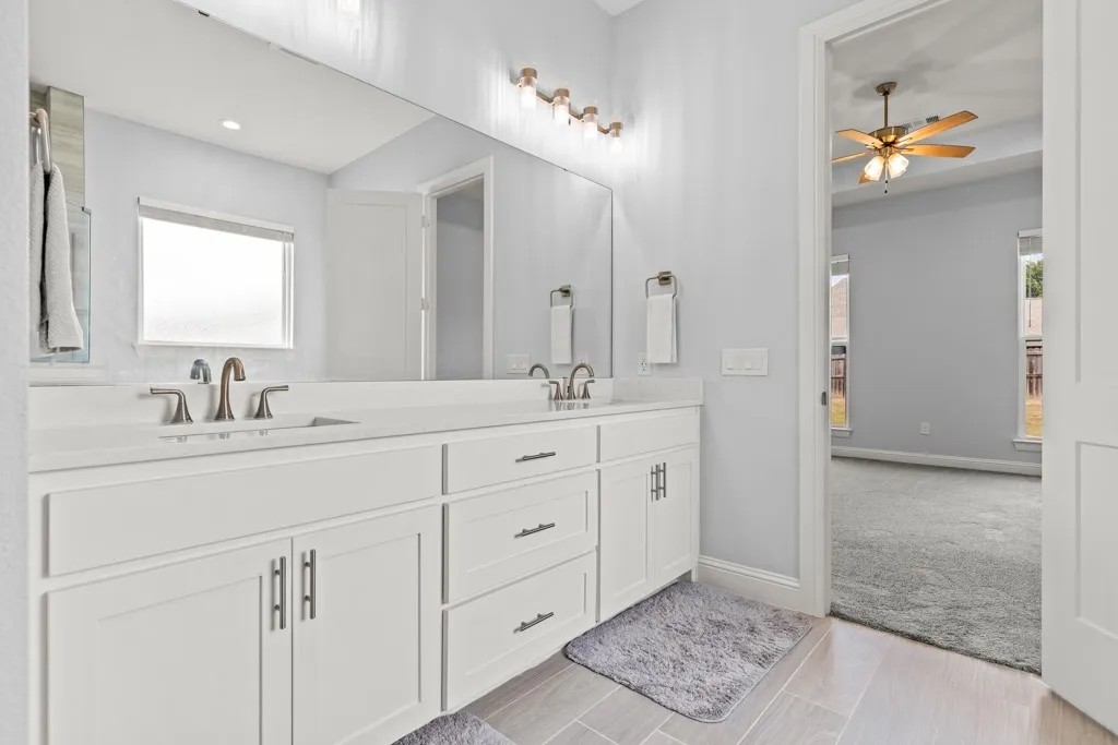 Double vanity with white cabinetry, light-colored countertops, and brushed nickel fixtures
