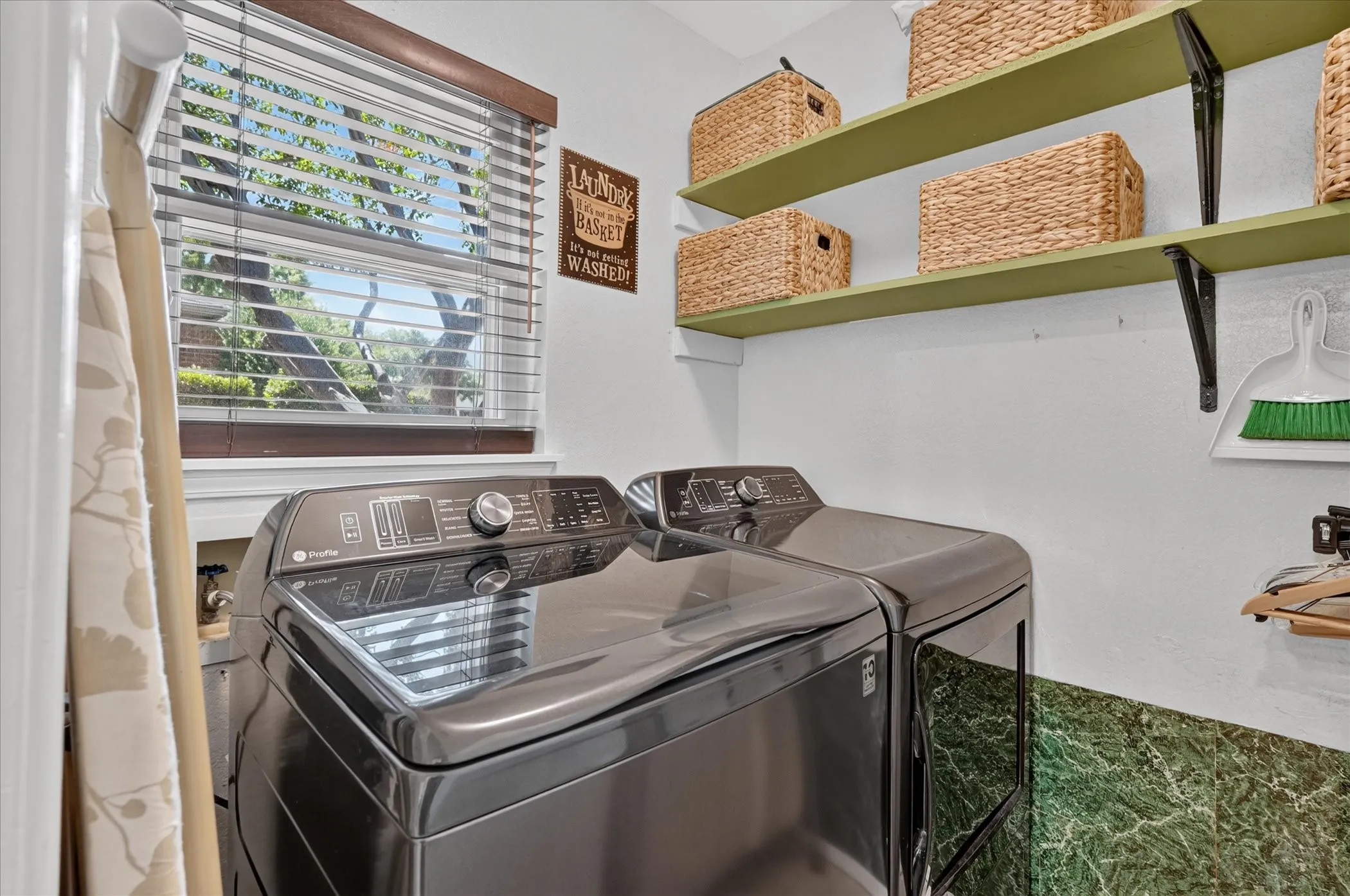 Dedicated laundry room offers space for a full-size washer and dryer, built-in shelving for storage, and a window providing natural light.
