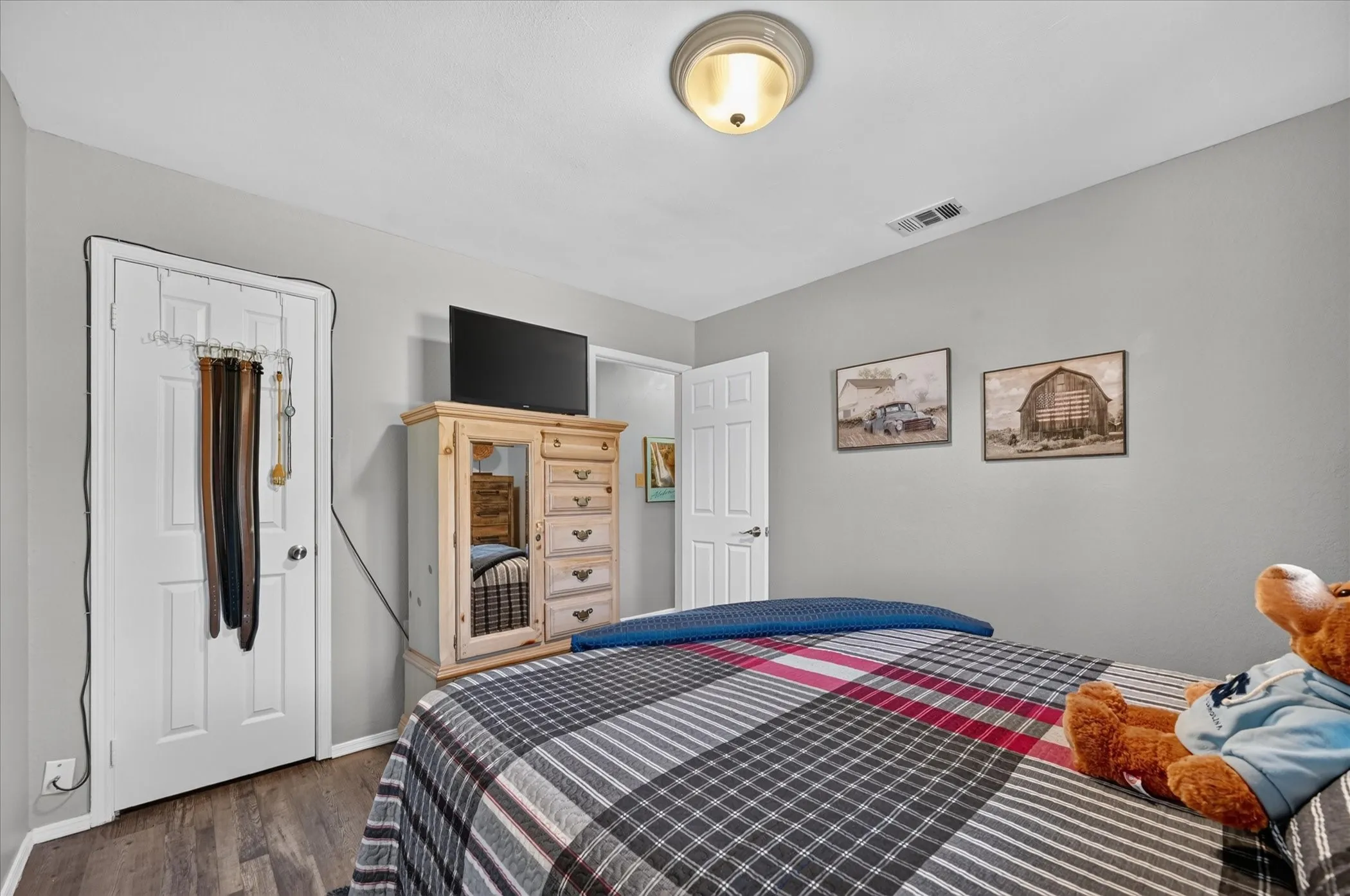 Additional view of the secondary bedroom highlights its comfortable layout, wood-look flooring, neutral finishes, and closet space.