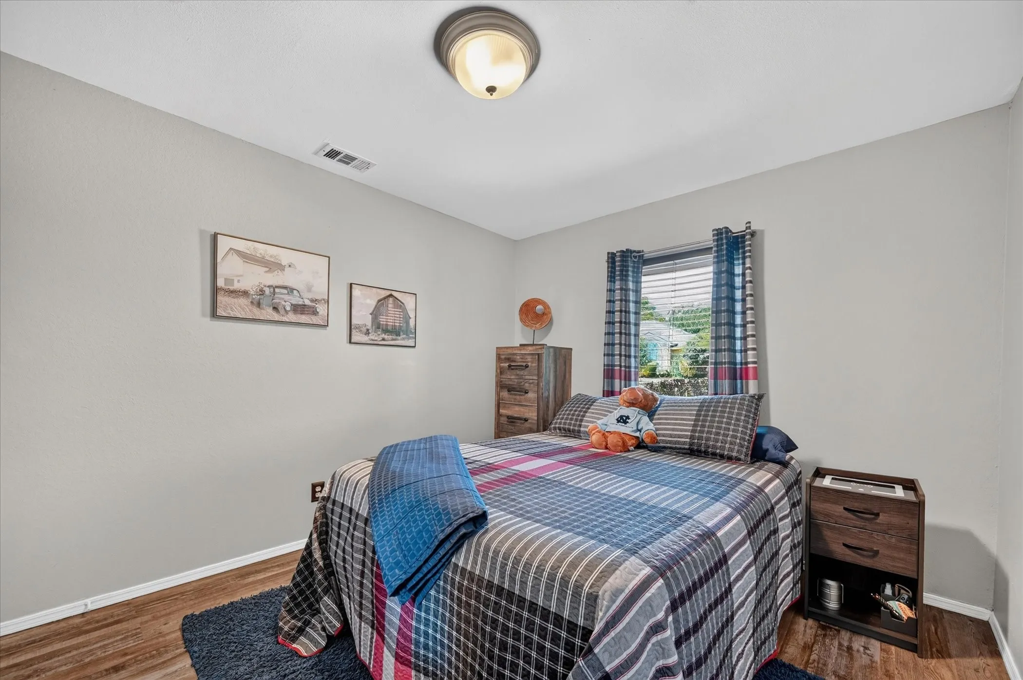 Additional view highlights the bedroom’s clean neutral palette, durable wood-look flooring, and flexible space for a variety of furniture arrangements.