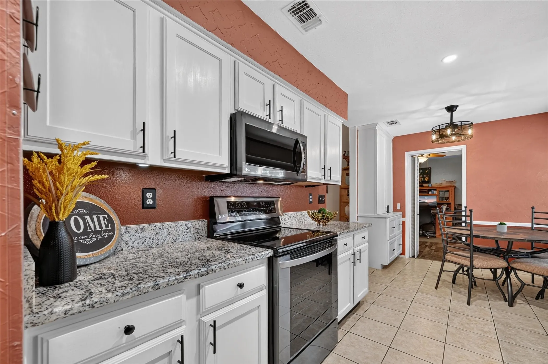 Efficiently designed kitchen pairs bright cabinetry with granite countertops, recessed lighting, and an adjoining breakfast area filled with natural light.