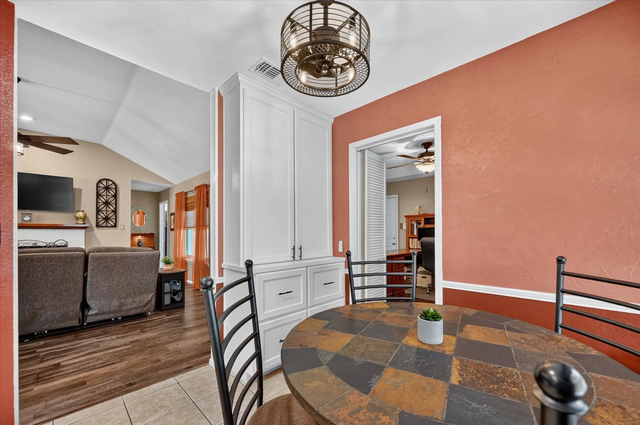 Cozy dining space connects seamlessly with the kitchen and living room, complemented by custom cabinetry and a distinctive statement light fixture.