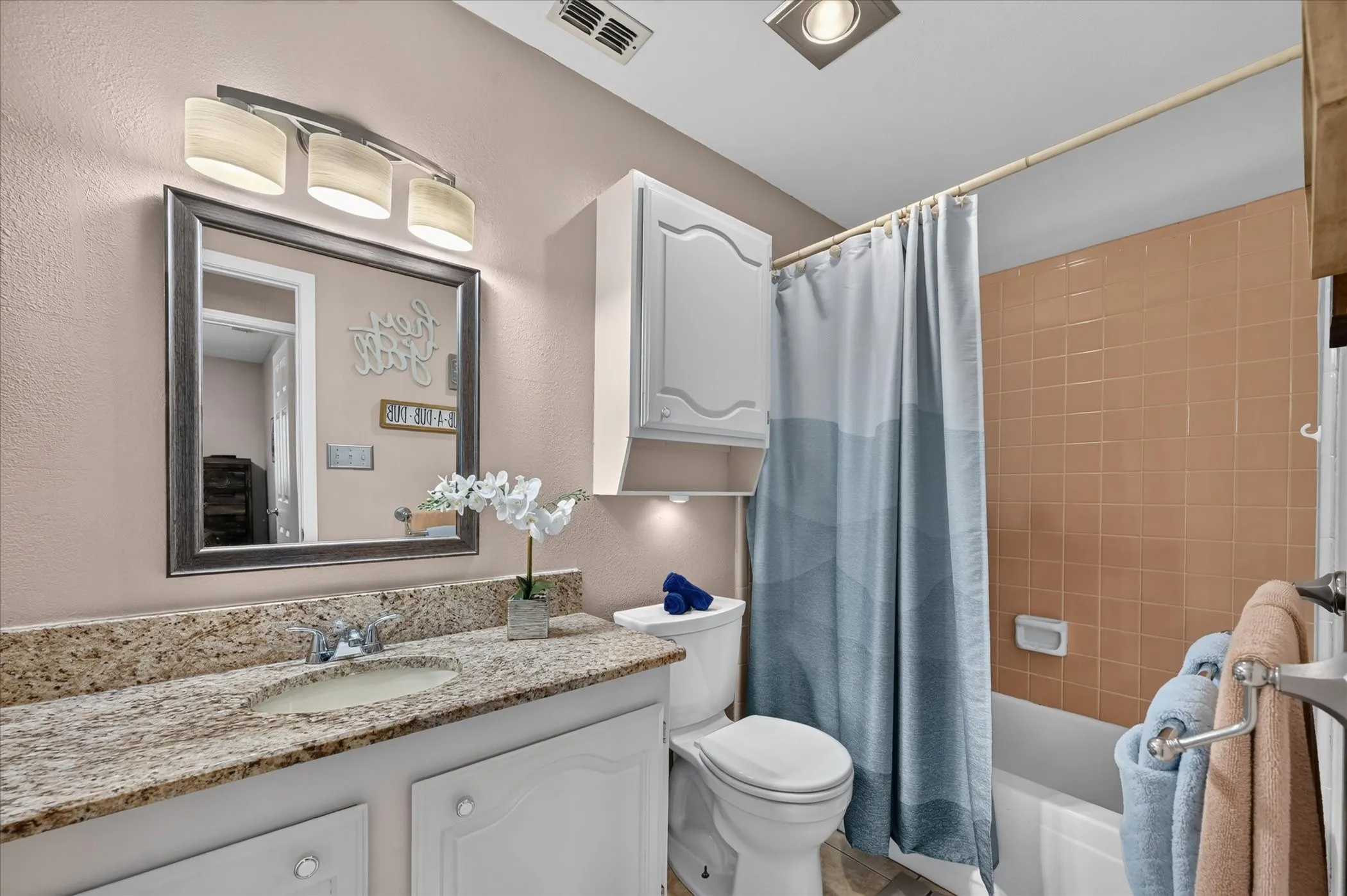 Full bathroom features a granite-topped vanity, white cabinetry, updated lighting, and a tub/shower combination.