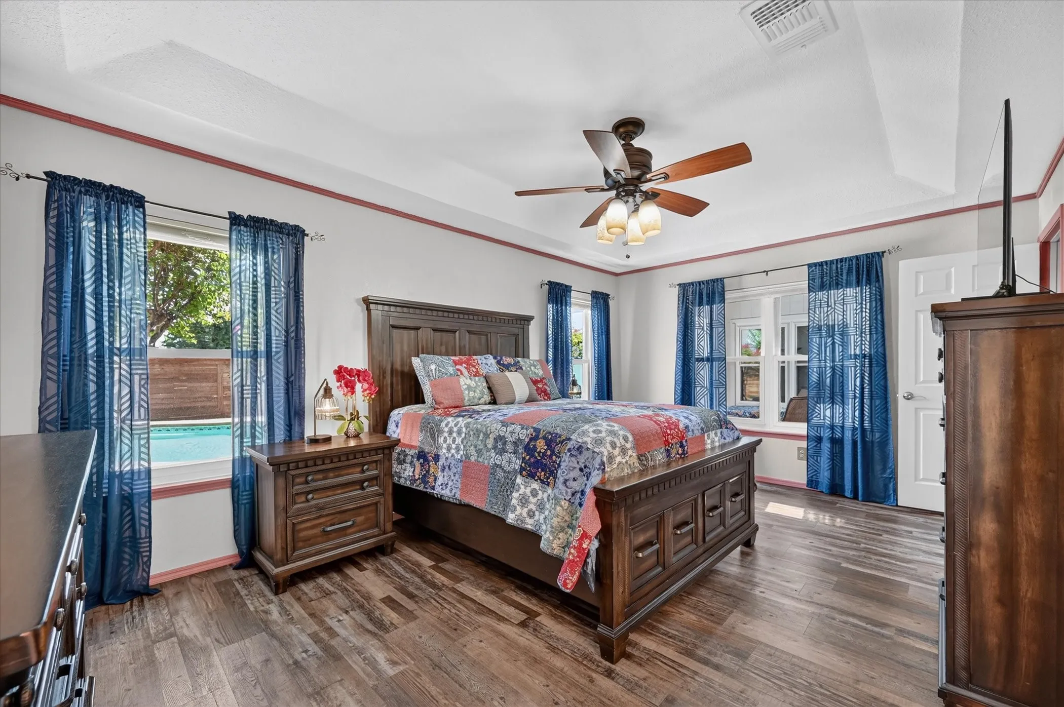 Bright primary suite is surrounded by multiple windows, providing abundant natural light and views of the backyard and swimming pool.