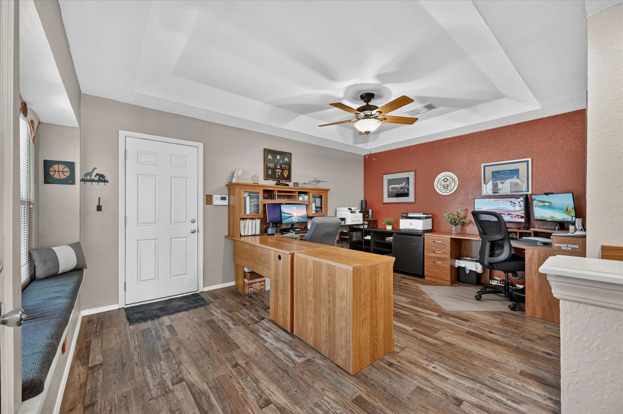 Generously sized dedicated office features a distinctive tray ceiling, abundant workspace, and a versatile layout ideal for a sophisticated home office or study.