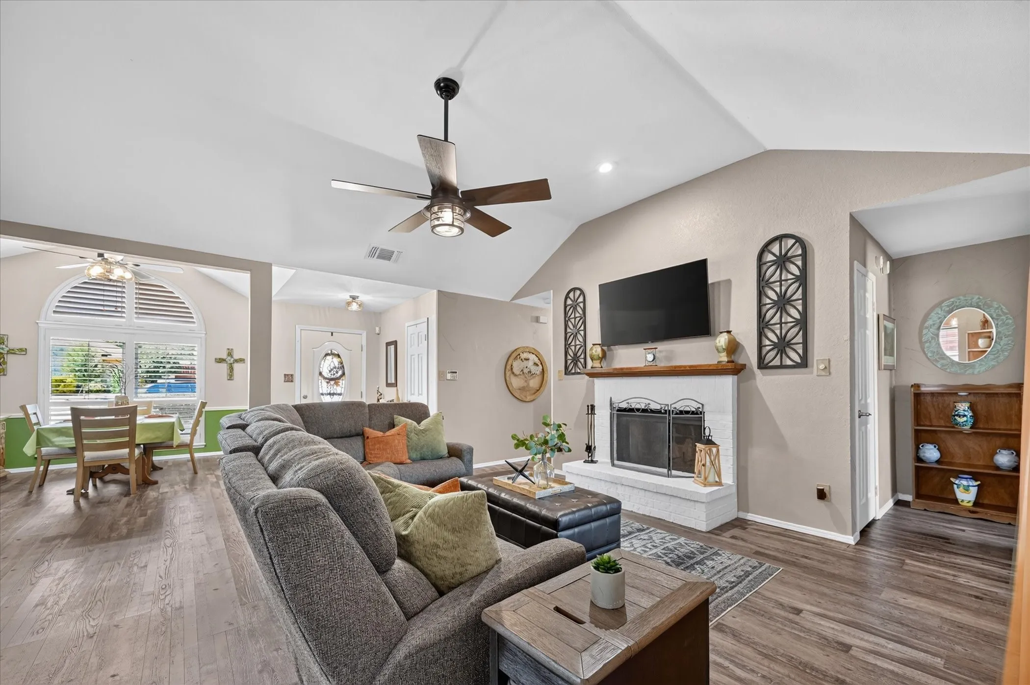 Beautifully appointed living space with soaring vaulted ceilings, a statement fireplace, beautiful flooring, and an open connection to the dining area.