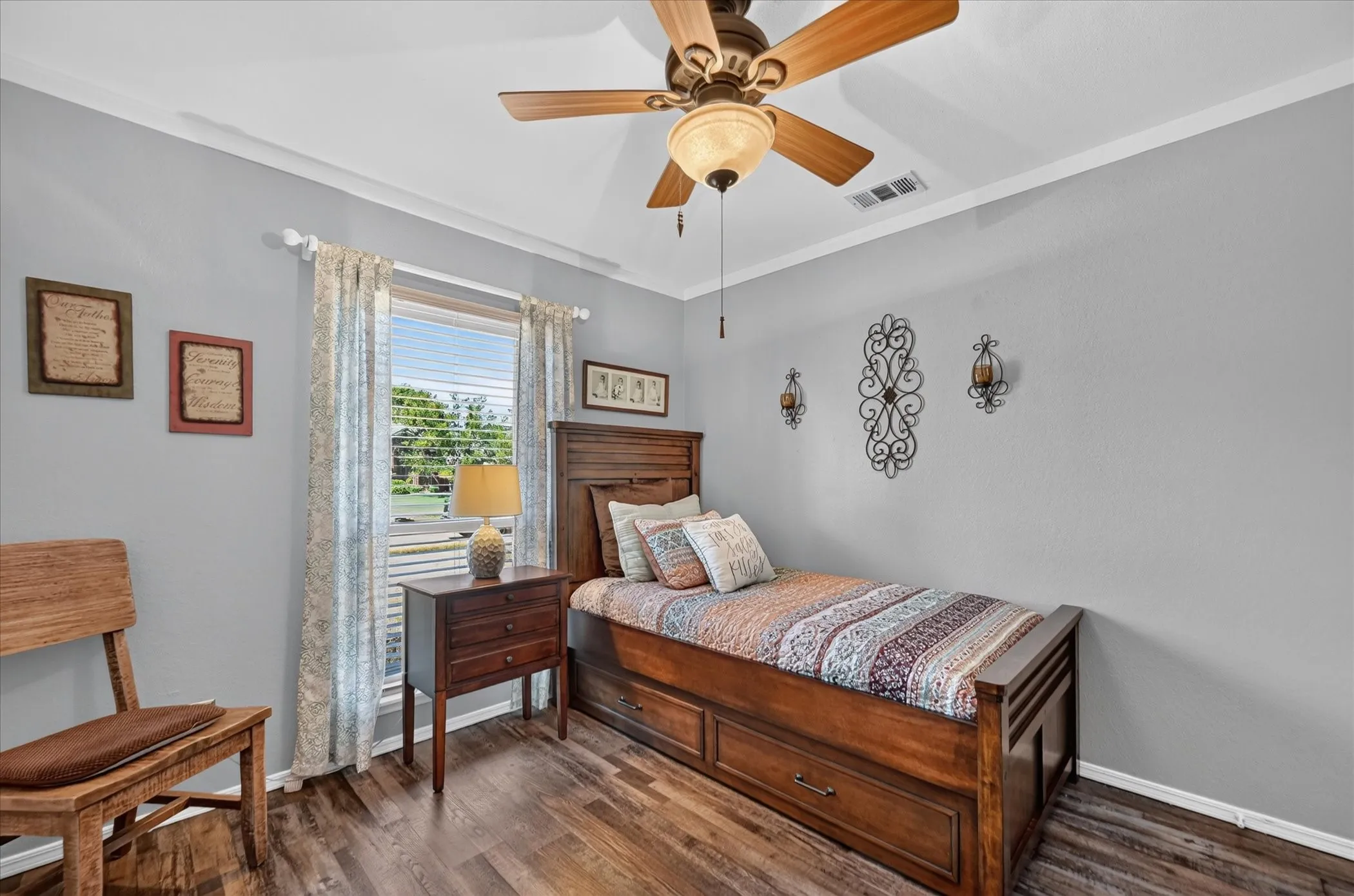 Another perspective of the secondary bedroom highlights its neutral finishes, generous wall space, ceiling fan, and bright window.