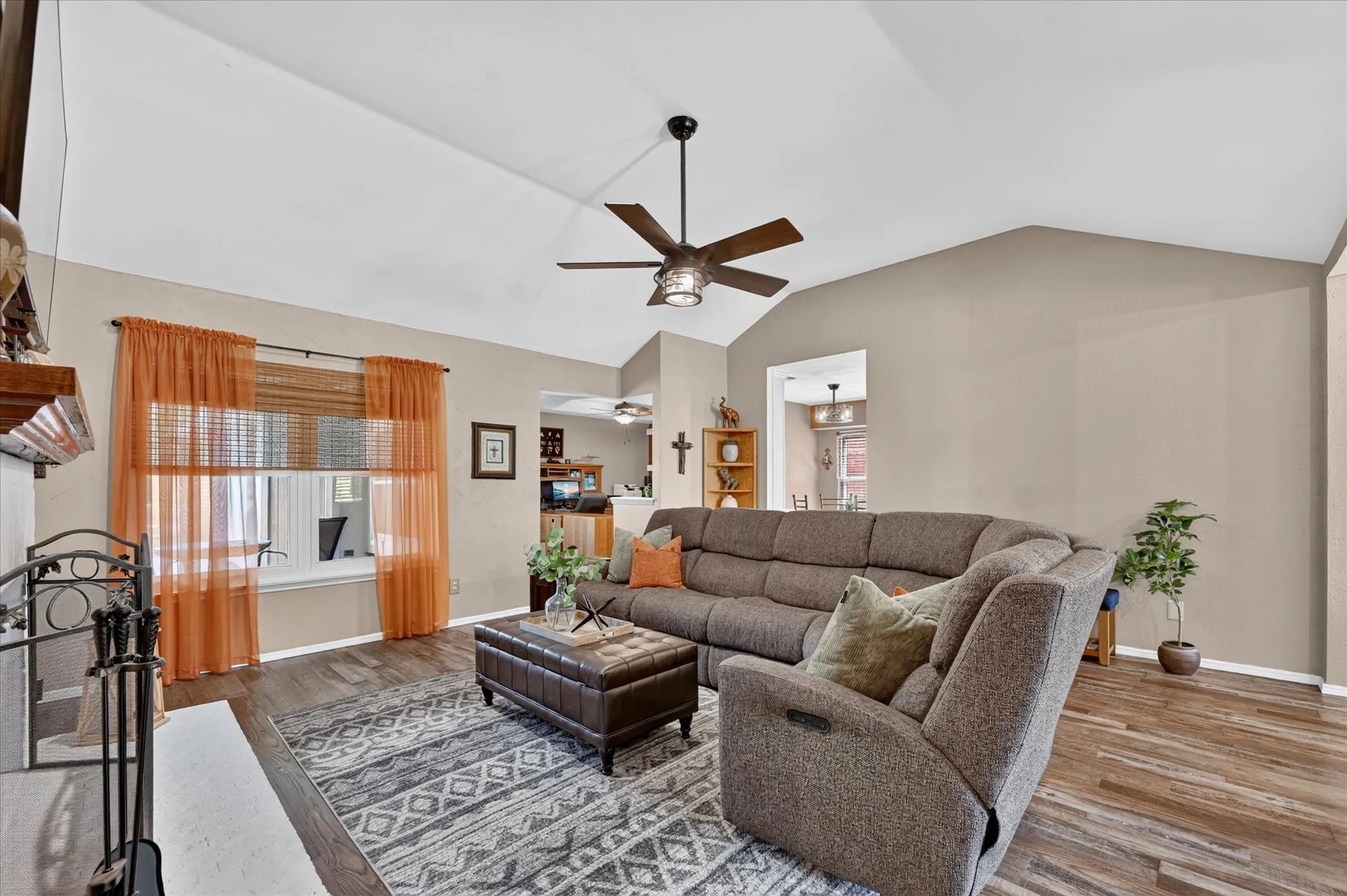 Spacious central living room offers vaulted ceilings, abundant natural light, warm wood-look flooring, and a comfortable layout designed for effortless everyday living.