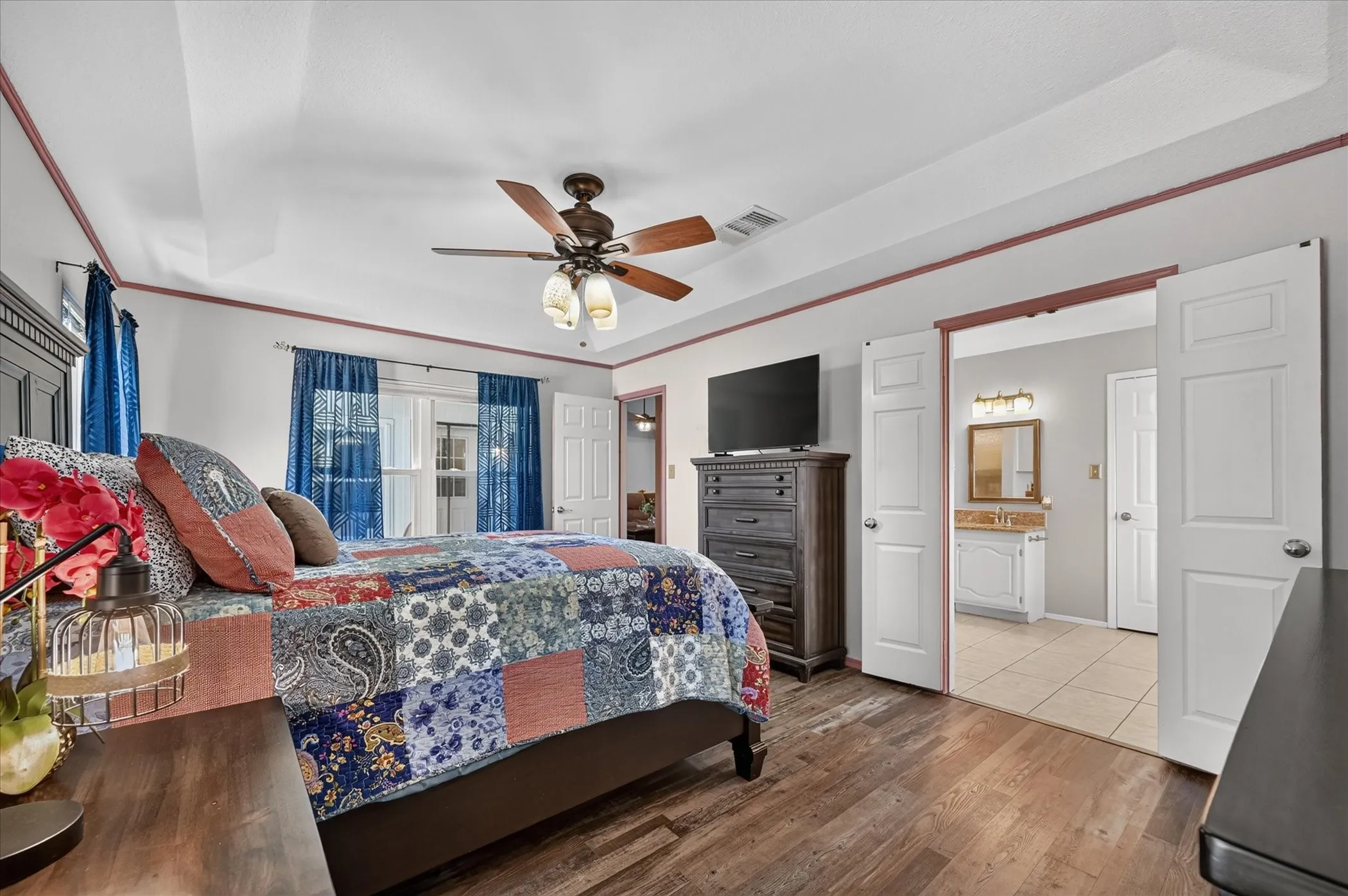 Another perspective showcases the primary bedroom’s spacious layout, tray ceiling, and direct access to the private bathroom.