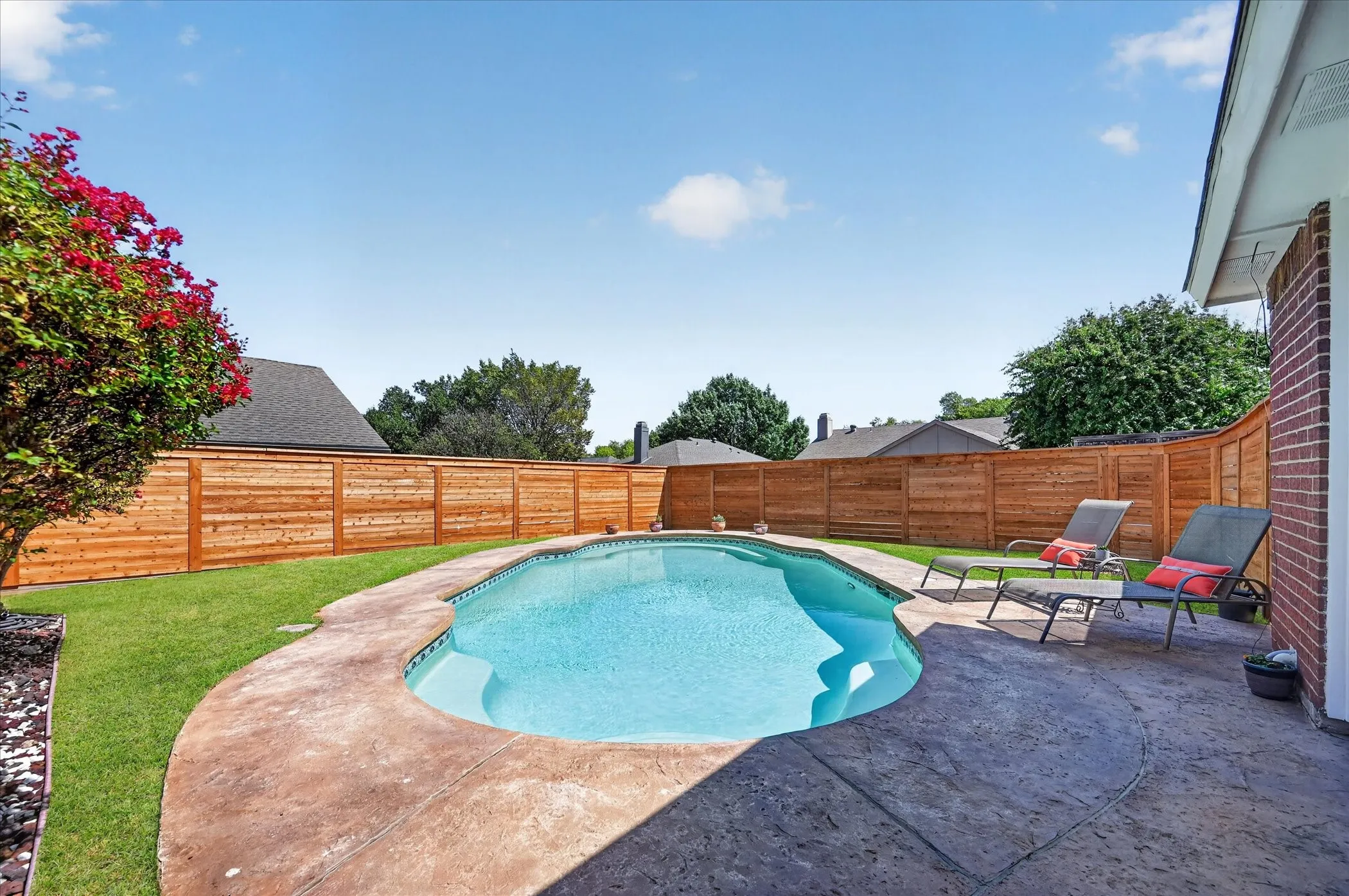 Resort-inspired outdoor setting centered around a beautifully designed pool with expansive decking and a secluded, fully fenced backyard.