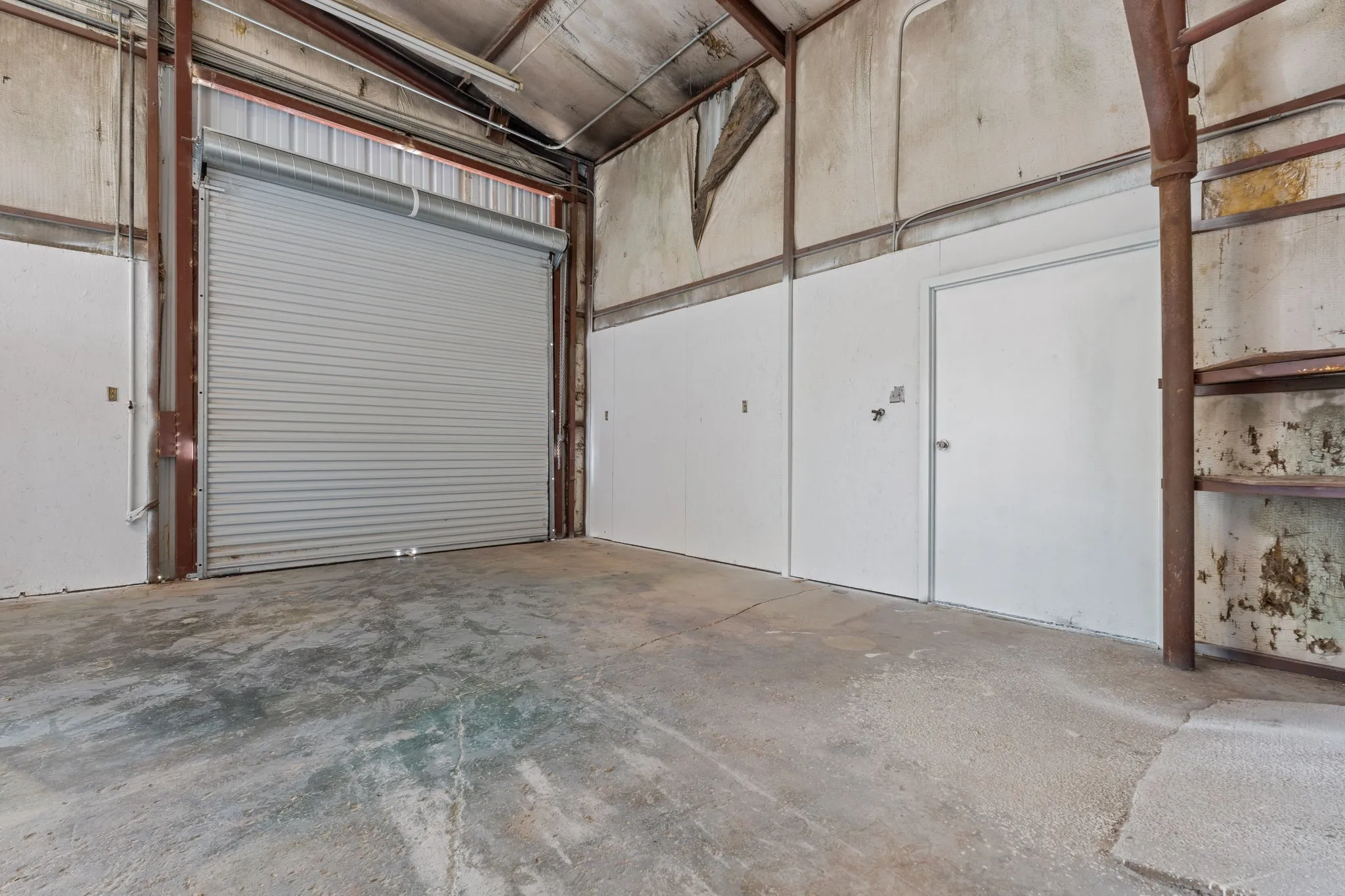 Workshop with 10-foot roll-up door facing Arvel Cir and walk-through access to the covered gravel area.